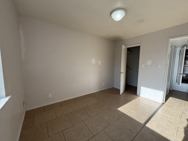 unfurnished bedroom with tile patterned flooring and baseboards