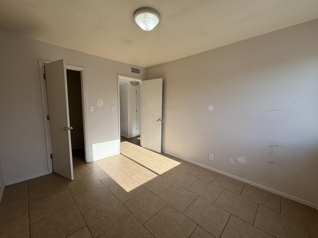 unfurnished bedroom featuring visible vents, tile patterned floors, and baseboards