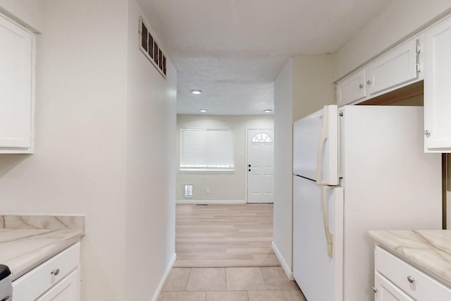 308 Garden Ave SW, Los Lunas, NM 87031 - kitchen with freestanding refrigerator, white cabinetry, visible vents, and light tile patterned flooring