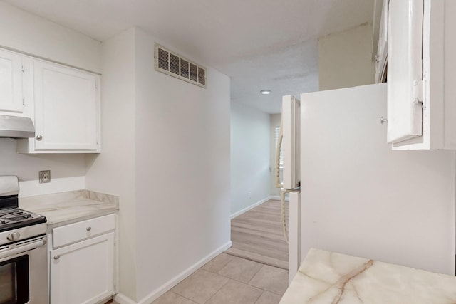 308 Garden Ave SW, Los Lunas, NM 87031 - kitchen with stainless steel range with gas stovetop, white cabinetry, light tile patterned floors, under cabinet range hood, and visible vents