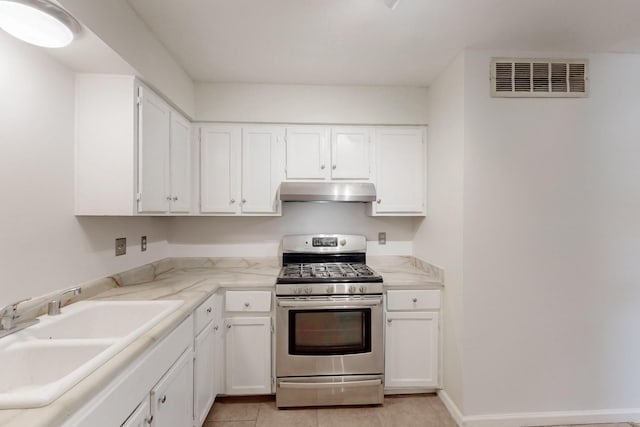 kitchen featuring visible vents, gas range, a sink, under cabinet range hood, and white cabinetry
