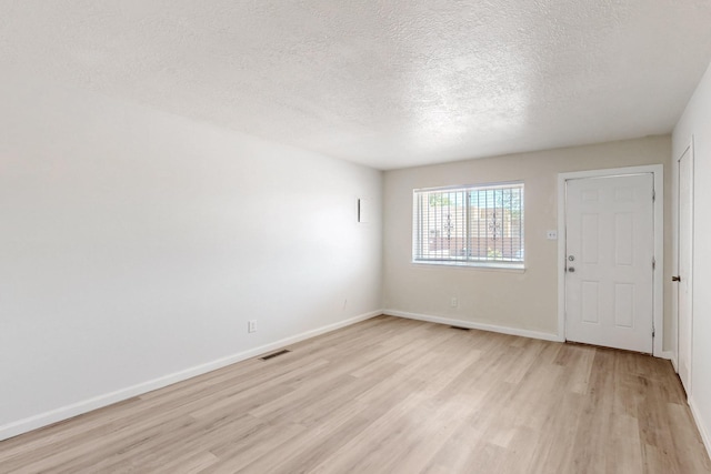 308 Garden Ave SW, Los Lunas, NM 87031 - empty room featuring baseboards, light wood finished floors, a textured ceiling, and visible vents