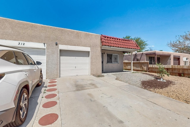 308 Garden Ave SW, Los Lunas, NM 87031 - view of front of property with a tiled roof, a garage, fence, concrete driveway, and stucco siding