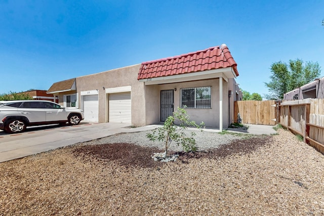 308 Garden Ave SW, Los Lunas, NM 87031 - view of front of home with a garage, fence, stucco siding, driveway, and a tile roof