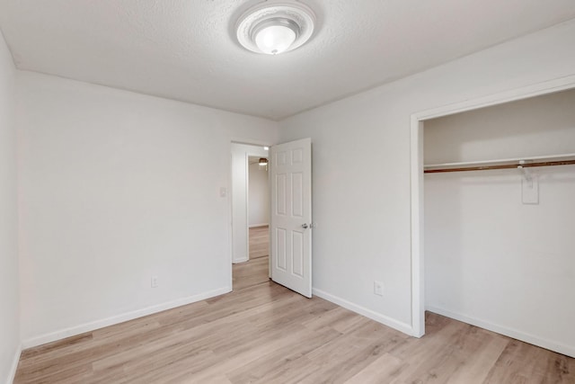 unfurnished bedroom featuring baseboards, a closet, and light wood-type flooring