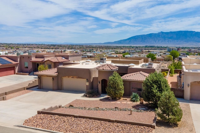 view of front facade with stucco siding, driveway, a mountain view, and an attached garage
