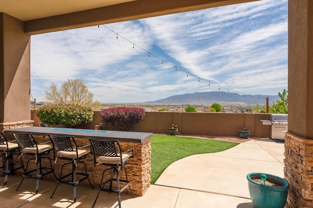 view of patio with a mountain view, a fenced backyard, grilling area, and outdoor dry bar