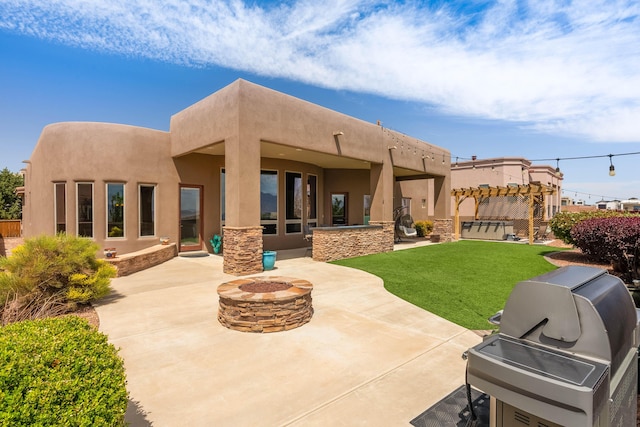 back of house featuring a lawn, an outdoor fire pit, stucco siding, and a patio area