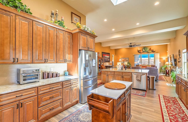 3919 Bryan Ave NW, Albuquerque, NM 87114 - kitchen featuring appliances with stainless steel finishes, a kitchen island, open floor plan, brown cabinetry, and light wood-style floors