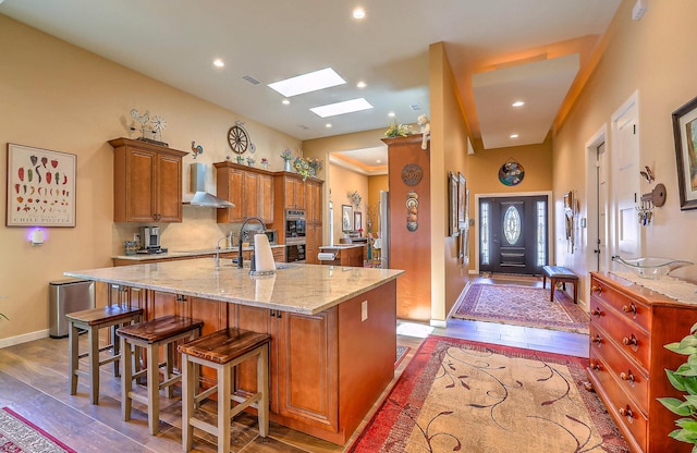 3919 Bryan Ave NW, Albuquerque, NM 87114 - kitchen with wall chimney range hood, dark wood-type flooring, a kitchen island with sink, brown cabinets, and recessed lighting