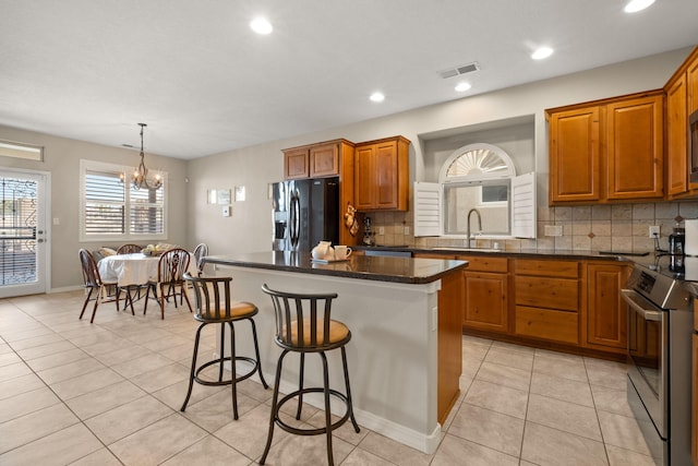 8719 Desert Fox Way NE, Albuquerque, NM 87122 - kitchen with a kitchen bar, a center island, stainless steel electric range, a sink, and black refrigerator with ice dispenser