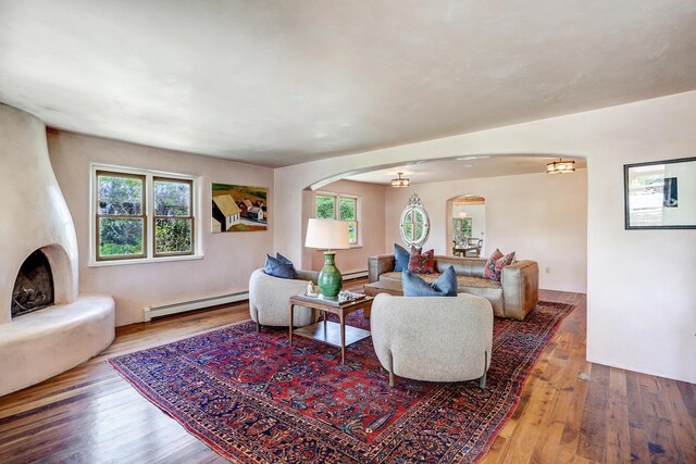 107 Rome Ln, Corrales, NM 87048 - living room featuring a baseboard radiator, arched walkways, hardwood / wood-style flooring, and a large fireplace