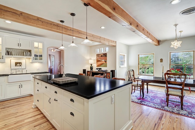 107 Rome Ln, Corrales, NM 87048 - kitchen featuring dark countertops, beamed ceiling, light wood-style floors, glass insert cabinets, and white cabinetry