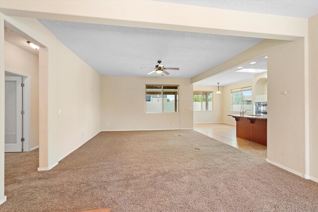 1047 Prairie Zinnia Dr, Bernalillo, NM 87004 - unfurnished living room featuring light carpet, a ceiling fan, a textured ceiling, and baseboards
