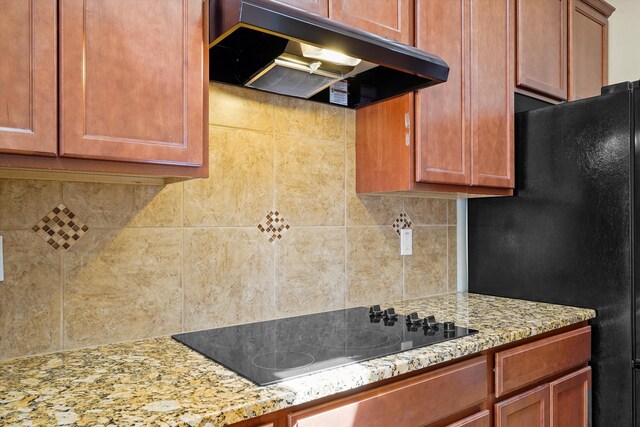 1047 Prairie Zinnia Dr, Bernalillo, NM 87004 - kitchen with under cabinet range hood, black appliances, decorative backsplash, light stone countertops, and brown cabinetry