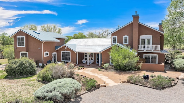 535 Cacahuate SW, Albuquerque, NM 87105 - back of house with stucco siding, metal roof, covered porch, and a chimney
