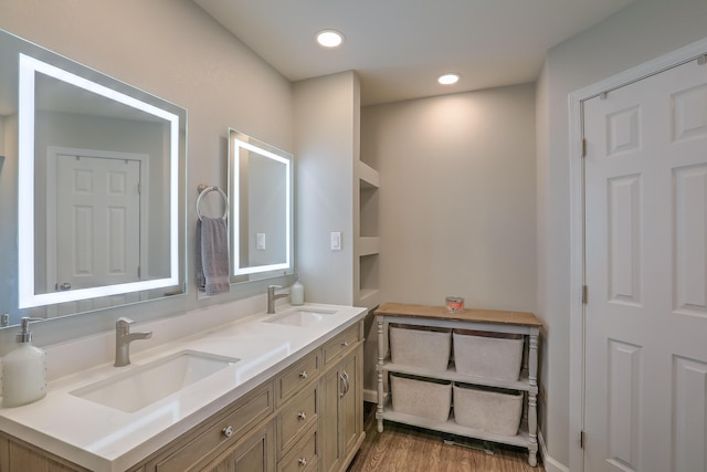 bathroom with a sink, double vanity, recessed lighting, and wood finished floors