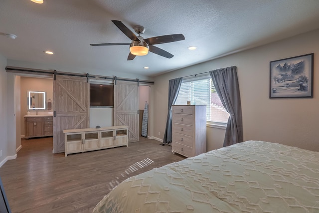 bedroom with baseboards, a barn door, wood finished floors, and recessed lighting