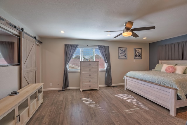 bedroom featuring a barn door, recessed lighting, baseboards, wood finished floors, and visible vents
