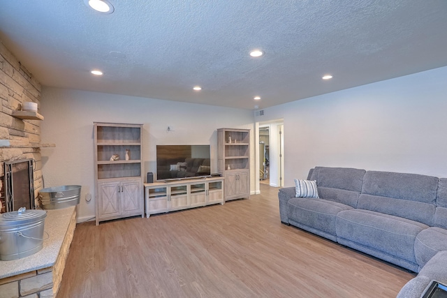 living room with recessed lighting, a textured ceiling, wood finished floors, and a fireplace