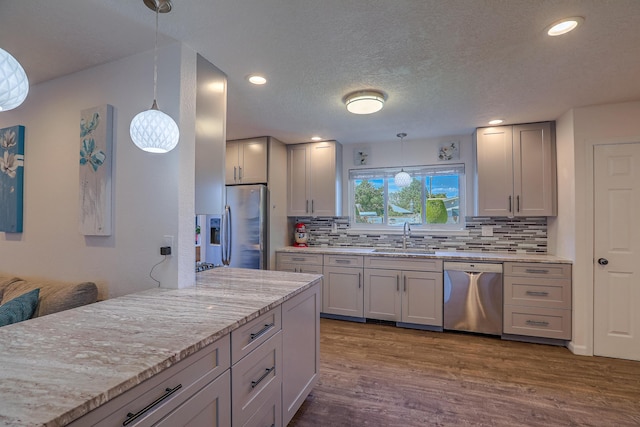 kitchen featuring light stone countertops, stainless steel appliances, decorative light fixtures, tasteful backsplash, and dark wood-style floors