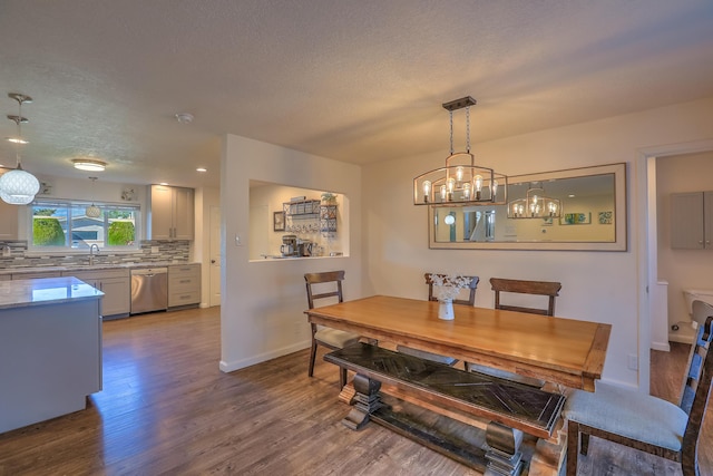 dining space with a textured ceiling, dark wood finished floors, baseboards, and an inviting chandelier