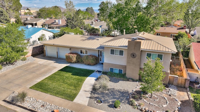 view of front facade featuring driveway, metal roof, fence, an attached garage, and stucco siding
