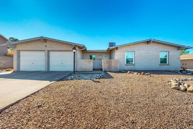 ranch-style home with a garage, fence, concrete driveway, and brick siding