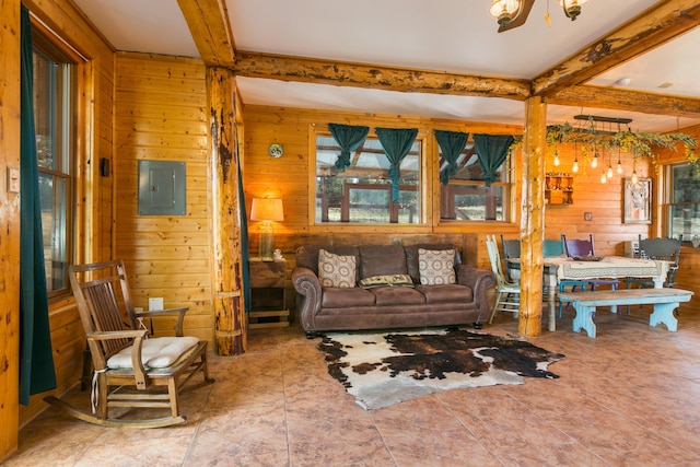living room with an inviting chandelier, beamed ceiling, electric panel, and wood walls