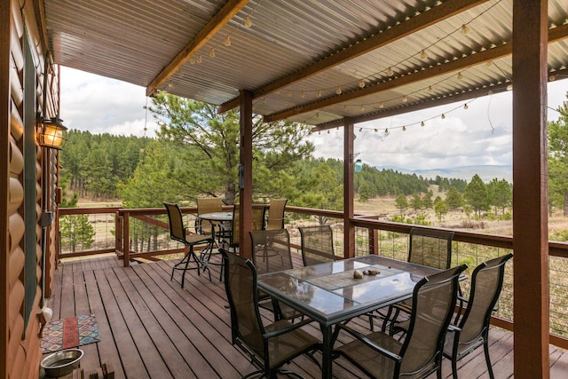 wooden deck featuring a view of trees and outdoor dining space