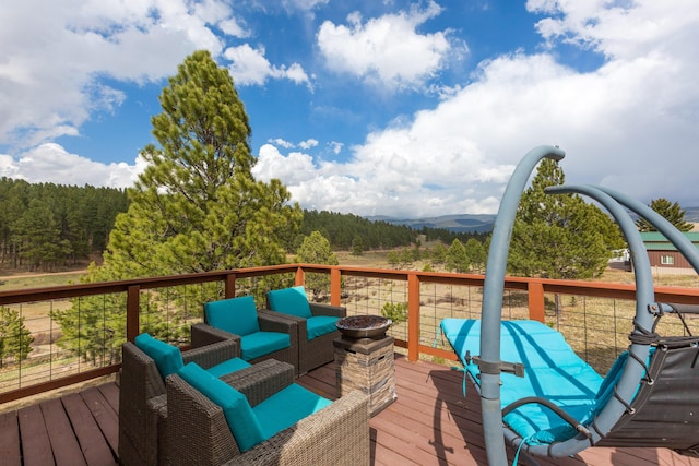 deck featuring a view of trees, an outdoor living space, and a mountain view