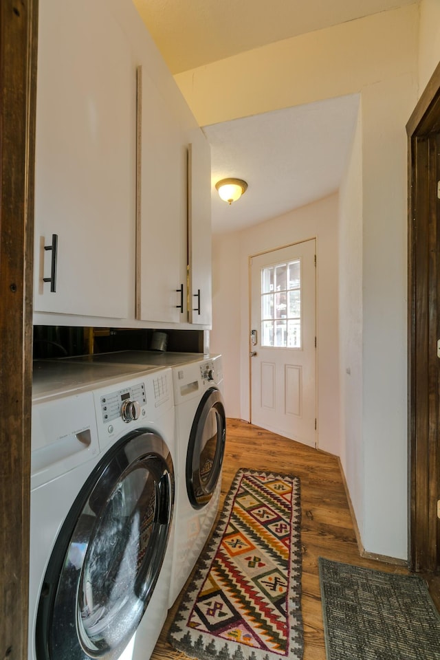 laundry room with cabinet space, wood finished floors, and washer and dryer