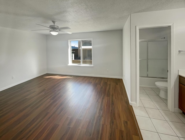 2009 Alama Dr NE, Rio Rancho, NM 87124 - unfurnished bedroom with light wood-style floors, a textured ceiling, a ceiling fan, baseboards, and ensuite bathroom