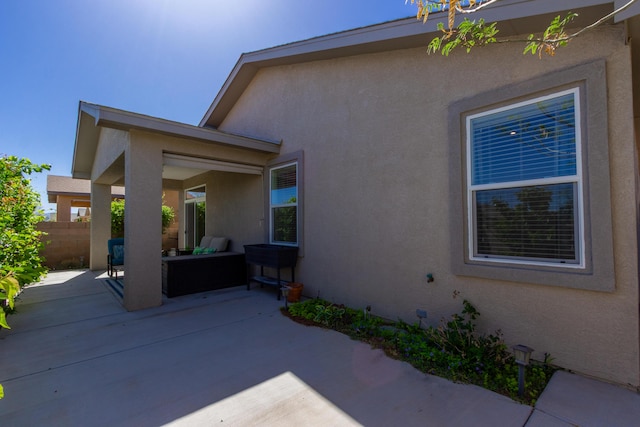 exterior space featuring fence, an outdoor hangout area, a patio, and stucco siding