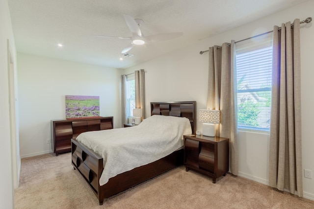 bedroom with a ceiling fan, light colored carpet, and multiple windows