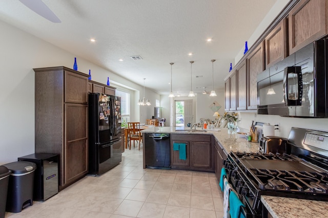 kitchen featuring a peninsula, black appliances, light stone counters, a sink, and a notable chandelier