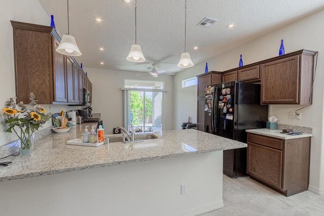 kitchen with a sink, freestanding refrigerator, a peninsula, recessed lighting, and visible vents