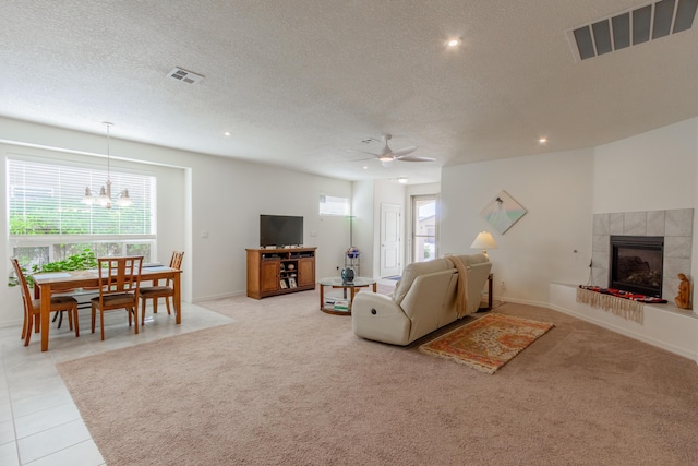 living area featuring a textured ceiling, visible vents, and ceiling fan with notable chandelier