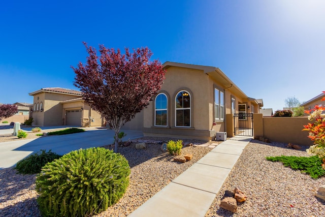 view of front of home featuring an attached garage, driveway, a gate, and stucco siding