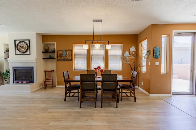 dining room with baseboards, light wood-type flooring, and a textured ceiling