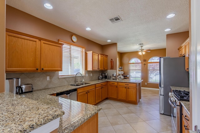 kitchen featuring a sink, stainless steel appliances, a ceiling fan, a peninsula, and visible vents