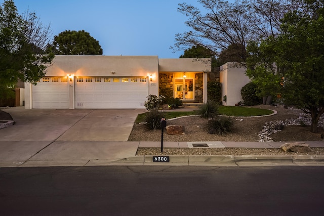view of front of house with a garage, stucco siding, driveway, and stone siding