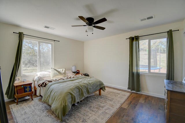 bedroom with a ceiling fan, baseboards, visible vents, and wood finished floors