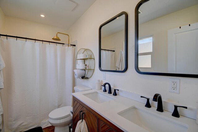 bathroom featuring double vanity, a sink, curtained shower, and toilet