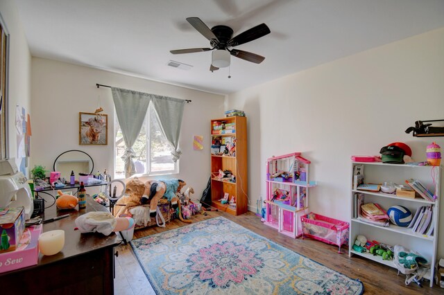 playroom with ceiling fan, wood finished floors, and visible vents