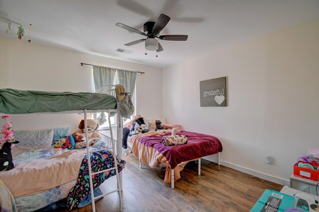 bedroom with baseboards, ceiling fan, wood finished floors, and visible vents