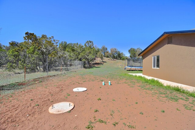 view of yard with a trampoline and fence