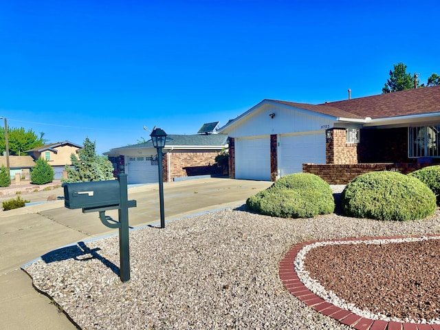 single story home with an attached garage, roof with shingles, driveway, and brick siding