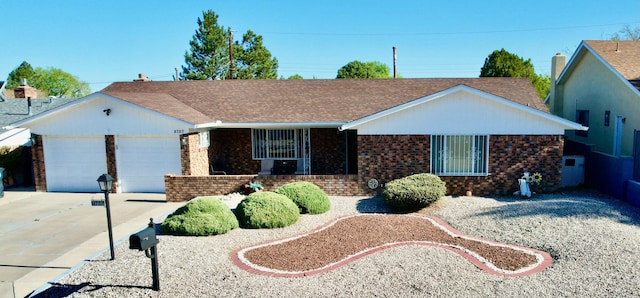 single story home featuring roof with shingles, an attached garage, driveway, and brick siding