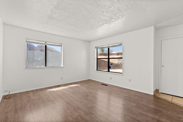 5812 Alegria Rd NW, Albuquerque, NM 87114 - empty room with visible vents, a textured ceiling, and wood finished floors
